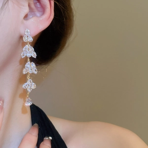 Detail of elegant gold leaf tassel earrings with sparkling crystals on a model