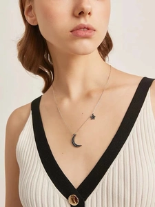 Close-up of crescent moon and star pendant necklace with pave dark crystals on model