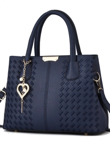 Détail d'un sac à main bleu marine en cuir grainé avec breloque cœur perlé et finitions dorées