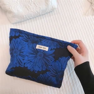Detail of blue floral canvas makeup bag with embroidered texture and simple wish label