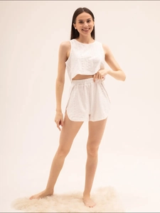 Gros plan détaillé sur la broderie anglaise blanche d'un ensemble de pyjama deux pièces doux