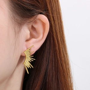 Detail view of gold plated titanium sunburst earrings worn by a fashion model on white