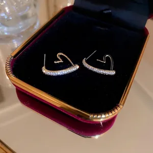 Boucles d'oreilles cœur dorées avec zircons sertis dans un écrin à bijoux rouge