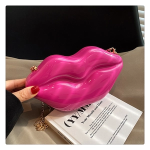 Detail shot of a hot pink lip-shaped acrylic box bag with a gold metal chain strap