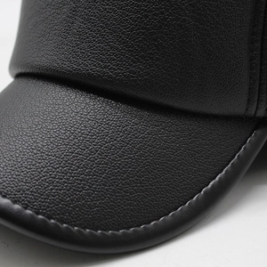 Detail of black leather texture and stitching on an elderly man winter ear protection cap