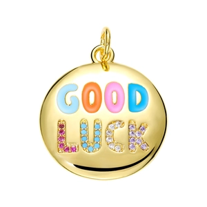 Macro view of round gold pendant with Good Luck enamel lettering and colorful zircons