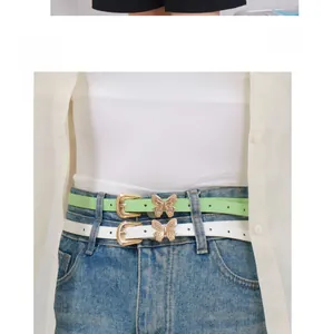 Detail of trendy butterfly buckle on slim mint green and white faux leather belts