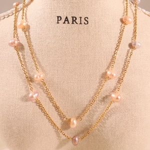 Elegant gold double-layer necklace with natural freshwater pearls on a linen mannequin