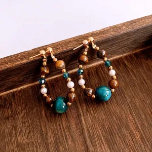 Vintage beaded drop earrings with tiger eye stone and blue beads on a wood surface