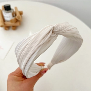 Detail of elegant white pleated headband featuring a chic knot design and textured fabric