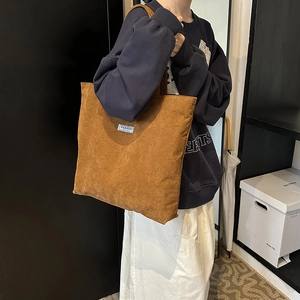 Detail of brown corduroy tote bag showing material texture and shoulder strap fit