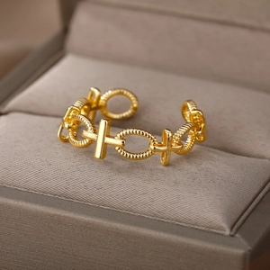 Detailed view of golden chain link ring with cross design on brown velvet display