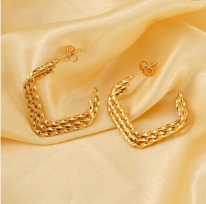 Vue détaillée de boucles d'oreilles torsadées dorées sur un tissu en soie champagne