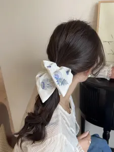 Detail of white satin hair scrunchie with intricate blue shell and sea snail embroidery