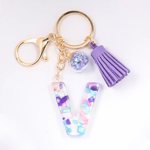 Detail of crystal resin letter V keychain with purple tassel and gold hardware