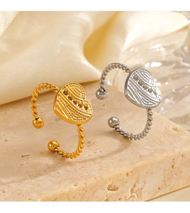 Detail shot of heart-shaped gold and silver rings on a textured stone surface