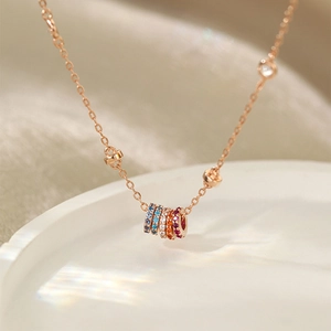 Macro view of rose gold necklace with five-color zircon rings on silk and ceramic