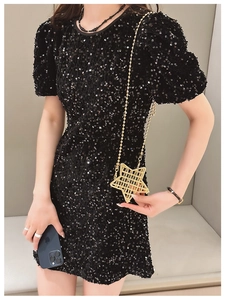 Detail of a golden star-shaped metal crossbody bag paired with a black sequin dress