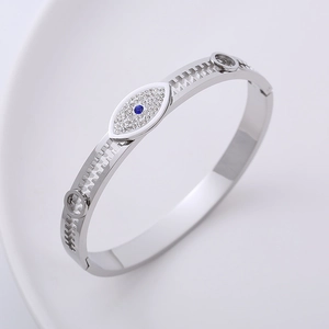 Polished silver evil eye bangle featuring gear-shaped hollow edges and sparkling crystals