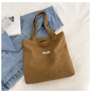 Close-up of brown corduroy tote bag featuring a stitched white label on fabric