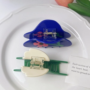 Detailed top view of tulip patterned hair claws on a ceramic plate with floral decor