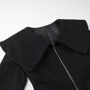 Detail shot of black wool coat featuring wide lapels and silver front zipper closure