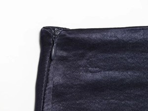 Detailed close-up of invisible zipper on navy blue satin mini dress with neat stitching