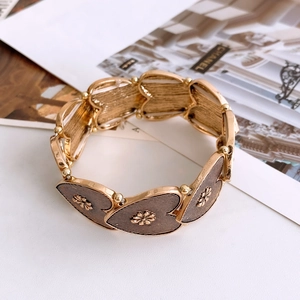 Detailed shot of golden elastic heart-shaped bracelet with embossed flower patterns