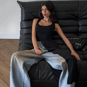 Détail d'un haut long noir sans manches et d'un jean large bleu clair porté par un mannequin