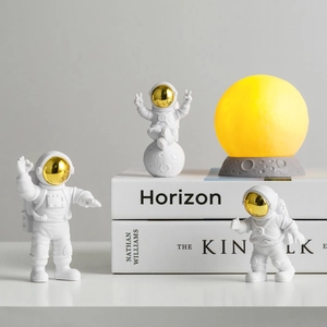 Detailed view of astronaut figurines with a glowing lunar lamp on a minimalist desk