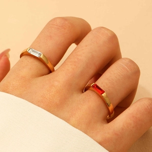 Close-up of gold-plated rings with rectangular red and white zircon stones on model fingers