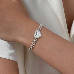 Detailed view of silver heart pendant bracelet with industrial links on a model's wrist