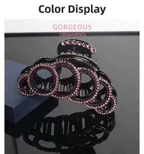 Macro shot of a large black claw clip adorned with radiant pink rhinestones on a wave design