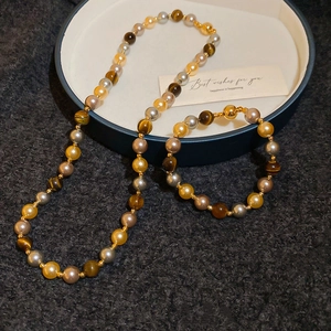 Vue rapprochée d'un ensemble de bijoux en œil de tigre et perles dans un coffret bleu
