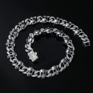 Detail of silver Cuban chain necklace featuring crystal skulls and black gem eyes