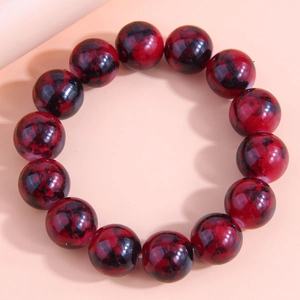 Macro shot of red and black marble texture glass beads on a minimalist beaded bracelet