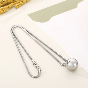 Close-up of polished silver ball pendant on sleek snake chain with elegant dried flowers