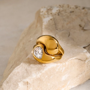 Vue macro d'une bague en acier doré 18K avec zircon goutte d'eau sur pierre claire