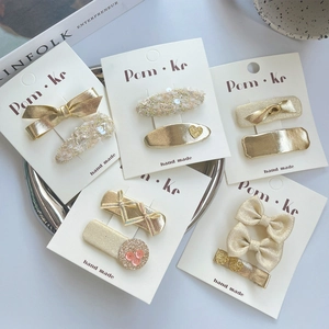 Golden heart sequin bow hair clips set on card display with minimalist magazine aesthetic