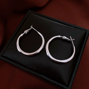 Detail of silver hoop earrings on black jewelry box with dark velvet background