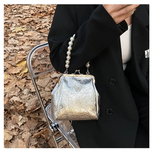 Detail of silver metallic handbag with pearl handle and butterfly clasp on a fall background