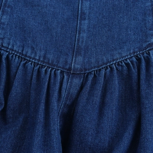 Dettaglio della vita di un abito in denim blu scuro con design a pieghe e cuciture fini