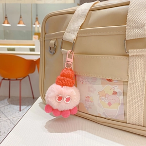 Rosa Plüschkrake Schlüsselanhänger mit Strickmütze an einer beigen Ledertasche im Detail