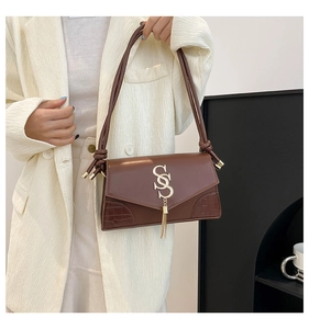 Detailed close-up of brown faux leather bag featuring golden SS logo and crocodile pattern