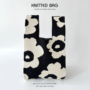 Detail of a black and white knitted bucket bag with a bold floral pattern and pastoral style
