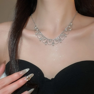 Close-up of elegant pearl and rhinestone tassel necklace worn on woman's neck
