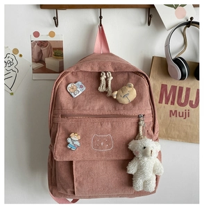 Detalle de textura de mochila rosa de pana con bonitos pines y colgantes