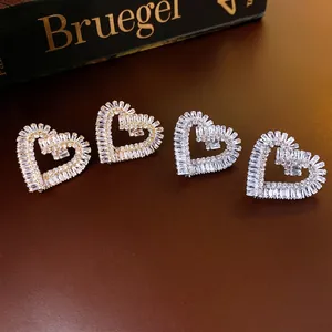 Elegant gold and silver heart stud earrings with cubic zirconia on a luxury background