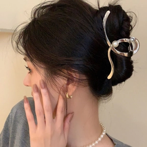 Detailed side view of silver metal Y2K hair claw with pearl accent in a hair bun style