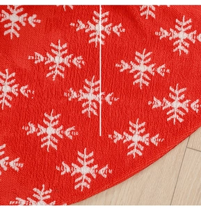 Detailed view of red knitted Christmas tree skirt featuring white snowflake jacquard pattern